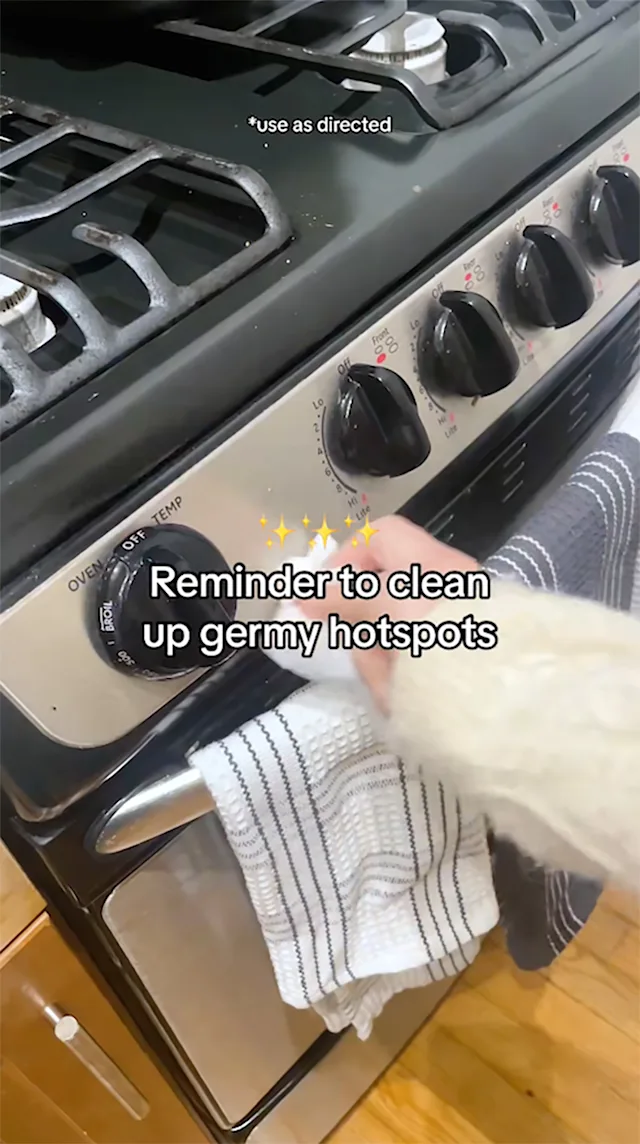 Reminder to clean up germy hotspots. Hand wiping control knob of stove.